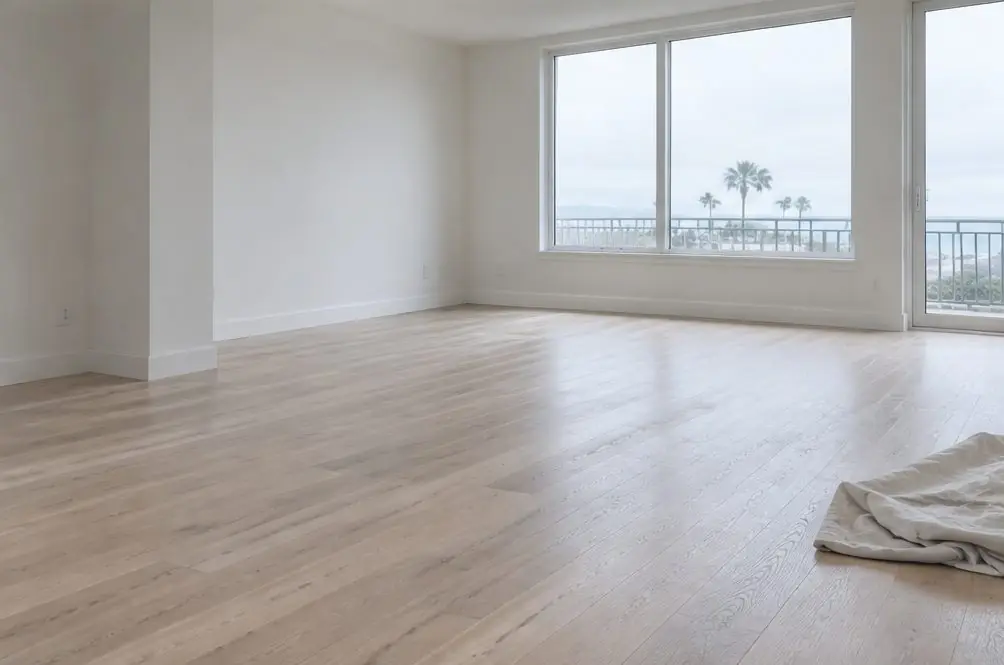 Illustration: an empty Oxnard apartment with a refinished oak floor, afternoon light across the boards and a folded drop cloth in the corner